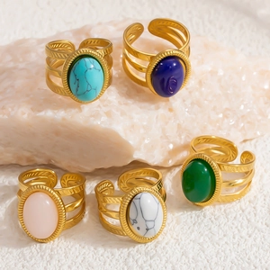 Macro detail of bohemian 18k gold rings with colorful natural stones on stone base