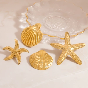 Detailed view of 18K gold starfish and seashell brooches on a marble tray