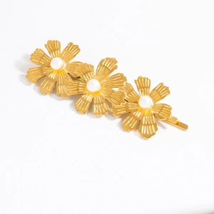 Détail de la pince à cheveux dorée avec trois fleurs de marguerite et perles blanches
