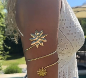 Detailansicht der goldenen Blumen-Armspange mit Hammerschlag-Textur am Oberarm