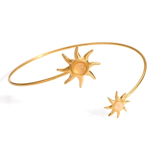 Detail eines vergoldeten 18K Armreifs mit Sonnendesign und orangem Schmuckstein