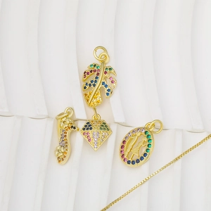 Gold pendants with monstera leaf and zircon stiletto charms on minimalist display