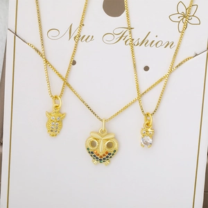Tres collares de búho dorados con circonitas y piedras de colores en cartón