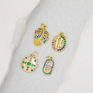 Gold-plated pendants featuring monstera leaf, oval portrait, and star with colorful zircon