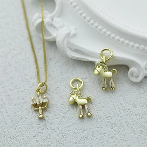 Detailed view of gold necklace pendants with horse and candlestick designs and zircons