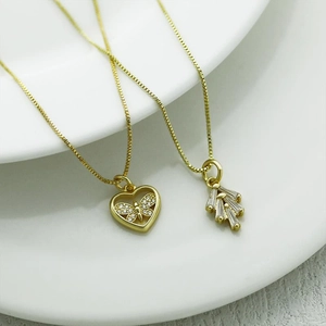 Close-up of golden necklaces featuring a hollow heart with a butterfly and zircon pendant