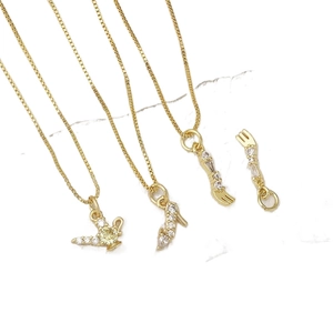 Gold-plated fairy tale charm necklaces with sparkling cubic zirconia on marble