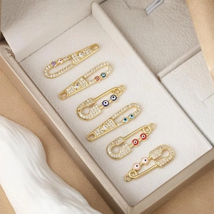 Vista macro de colgantes de imperdible bañados en oro de 18K con circonitas de ojo turco