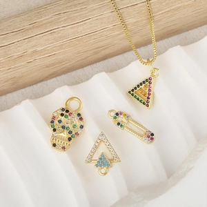 Goldene Kreuz- und Rautenanhänger-Halskette mit bunten Zirkonsteinen auf weißem Stoff