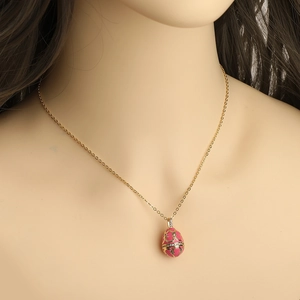 Detail eines rosa Fabergé-Stil Ei-Anhängers mit goldenem Muster an einer feinen Halskette