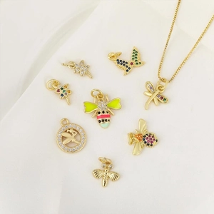 Golden bee and butterfly pendants with colorful cubic zirconia on minimalist white fabric