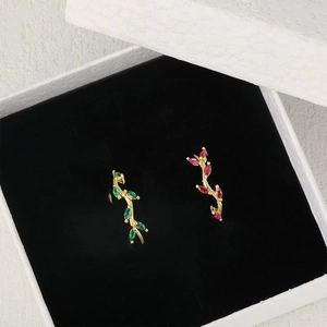Goldene Astringe mit grünen und rosenroten Marquise-Edelsteinen in einer weißen Geschenkbox