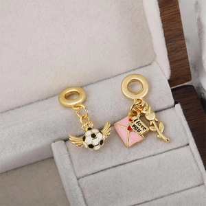 Macro shot of gold 18k plated soccer and heart envelope charms in a gift jewelry box