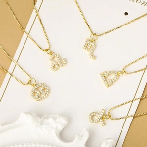 Detail van gouden sterrenbeeldhangers met zirkonia-steentjes aan fijne schakelkettingen