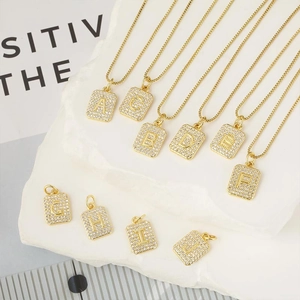 Dettaglio di ciondoli a lettera quadrati in oro con zirconi micro-pavé su basi in pietra