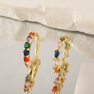 Elegant 18K gold-plated earrings set with colorful gemstones on a stone background