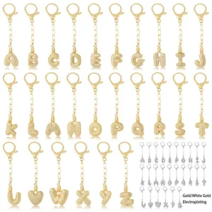 Porte-clés avec lettres initiales serties de zircone en finitions or et or blanc sur fond blanc