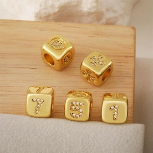 Dettaglio macro di ciondoli numerici placcati in oro con zirconi per gioielli DIY