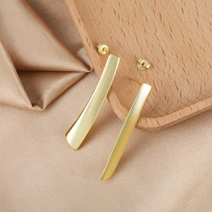Elegante lange goldene geometrische Stabohrringe auf Champagnerseide und Holztablett