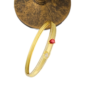 Elegant gold open bangle with red pear-cut gemstone and pavé crystal accents