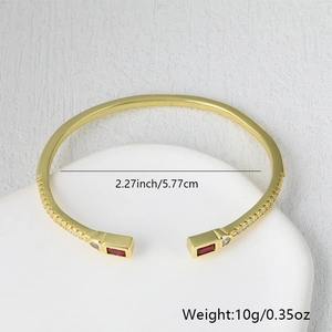 Detail of gold brass open bangle with red crystal and micro-pave cubic zirconia accents