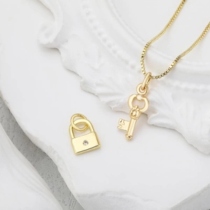 Set collana con pendente a chiave e lucchetto dorato su vassoio in pietra decorativo