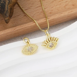 Golden evil eye pendant necklace with white crystals on a natural wood background