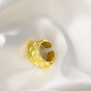 Elegante anillo abierto bañado en oro con diseño acolchado sobre fondo de seda blanca