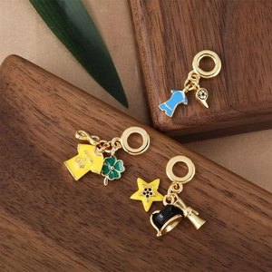 Charming gold-plated enamel pendants featuring soccer jerseys and stars on a wooden tray