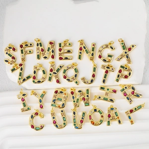 Set of 26 gold-plated alphabet pendants with vibrant colorful zircon stones on a white base