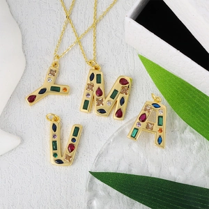 Detailed macro view of gold-plated necklaces with colorful cubic zirconia initial pendants