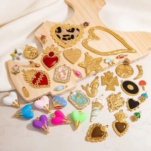 Flat lay of diverse gold-plated enamel charms including hearts and stars on wooden palette
