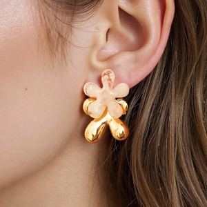 Detailed view of double-layer flower stud earrings in gold and marble resin on ear
