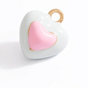 Detail of a double-layered heart pendant with white and pink enamel and gold loop