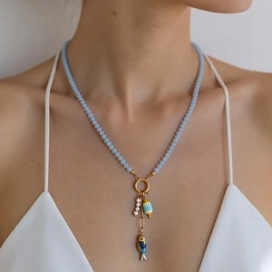 Detailopname van blauwe kralenketting met vishanger en parels bij het model