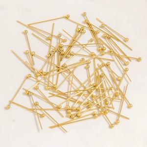Close-up of golden stainless steel ball head pins for DIY jewelry making on marble