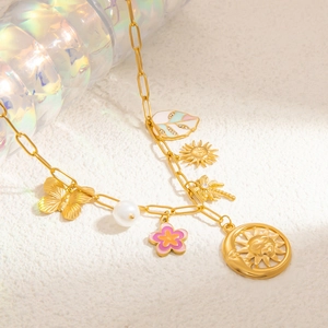 Dettaglio di collana placcata oro 18k con perle e ciondoli colorati su sfondo bianco