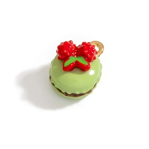 Dettaglio di un ciondolo macaron verde in lega con bacche rosse e anello d'oro