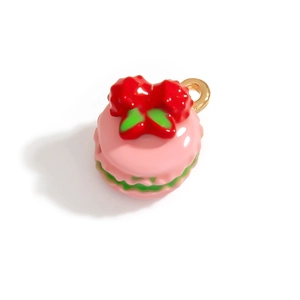 Vista macro di un ciondolo macaron rosa con fiocco rosso e anello in metallo oro