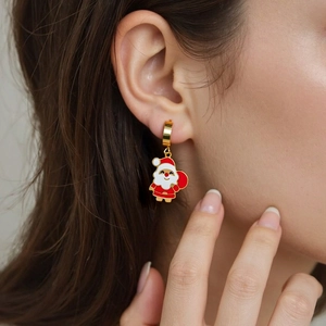 Close-up of golden Christmas Santa Claus charm earrings worn on the earlobe