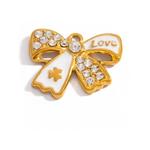 Macro detail of golden bow pendant with white enamel, rhinestones and Love engraving