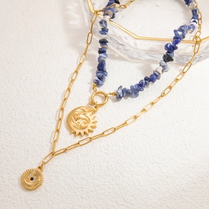 Detail van boho gelaagde ketting met blauwe natuursteen en gouden zon- en maan-hanger