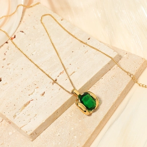 French vintage gold emerald geometric earrings on a travertine stone surface