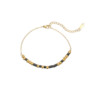 Détail d'un bracelet doré avec perles noires mates et fermoir mousqueton réglable