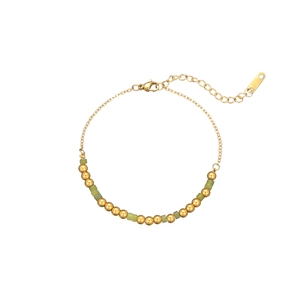 Détail du bracelet chaîne en perles dorées avec pierres cubiques vertes et fermoir mousqueton