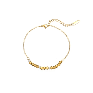 Détail d'un bracelet doré avec perles blanches en pierre naturelle et fermoir mousqueton