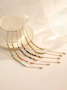 Détail de 6 chaînes dorées avec perles de cristal colorées sur le bord d'une tasse