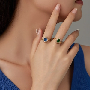 Détail de bagues dorées élégantes avec pierres en zircon ovale bleu et vert sur la main