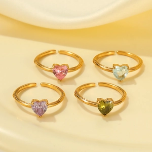 Détail de quatre bagues ajustables en plaqué or avec zircons colorés en forme de cœur