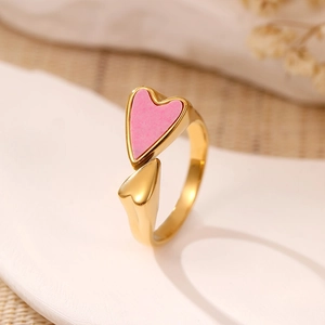 Gros plan d'une bague ouverte dorée avec détail de cœur en émail rose et poli